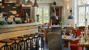 Eine Bar mit Hockern, hängenden Lampen und einer Wand, die mit Fischmotiven verziert ist.