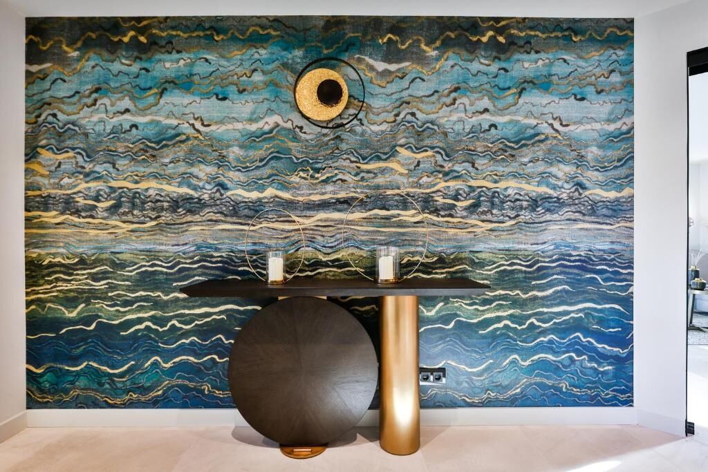 Un interior moderno con un mural texturizado, una mesa redonda negra y un pilar dorado.
