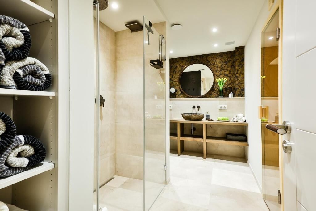 Casa de banho moderna com cabine de duche em vidro, espelho redondo e toucador com lavatório.