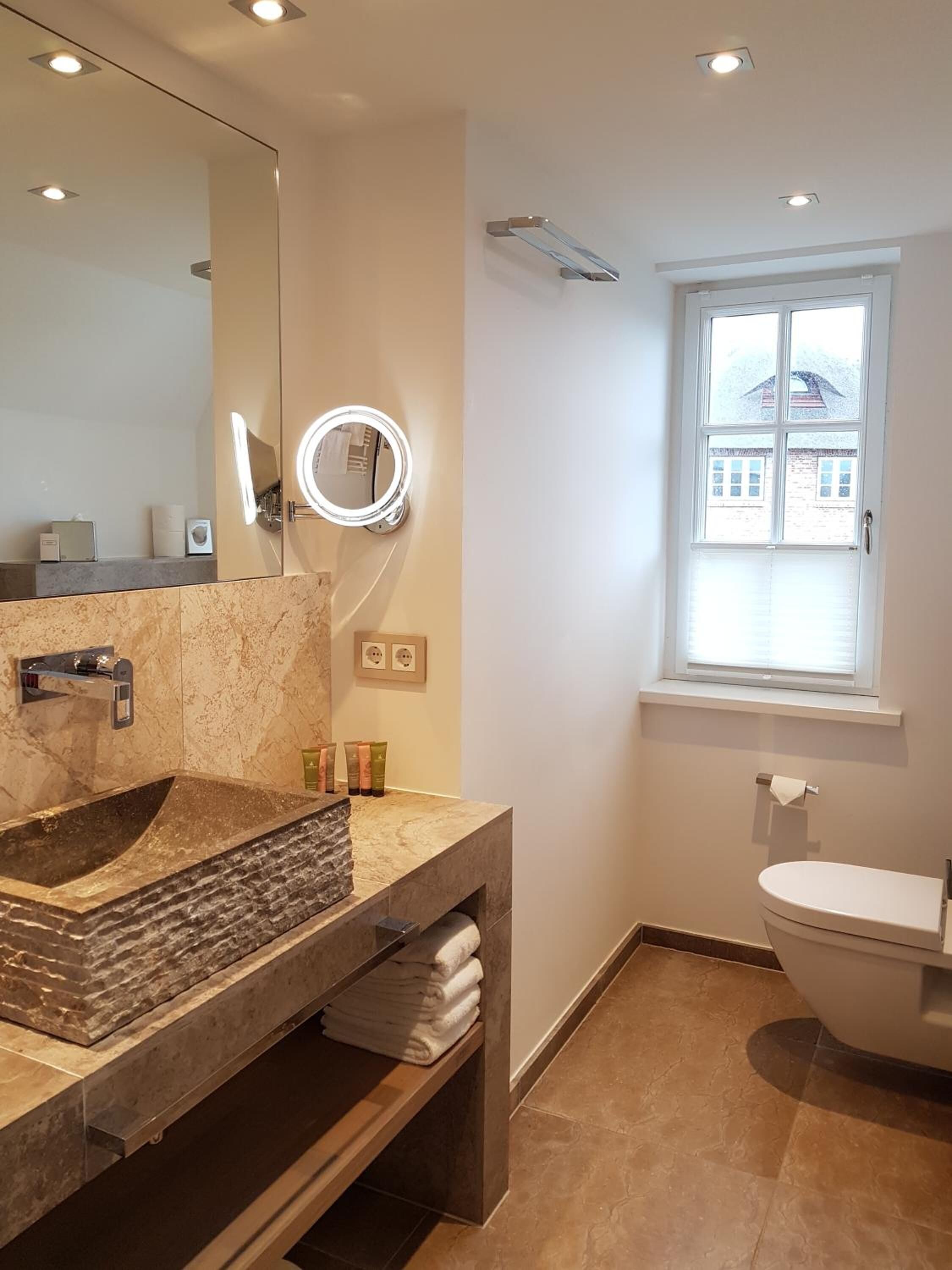 A modern bathroom with a large mirror, a built-in sink, and a toilet.