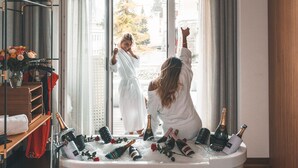 A room with a bathtub filled with champagne bottles and ice, a guitar, and a mirror reflecting a person in a robe. - Hard Rock Hotel Davos (Davos)