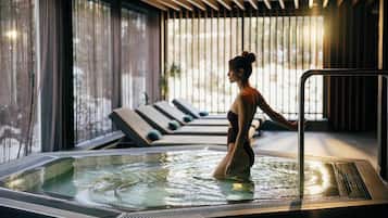 Une personne dans un jacuzzi, avec vue sur des chaises longues et un mur vitré.