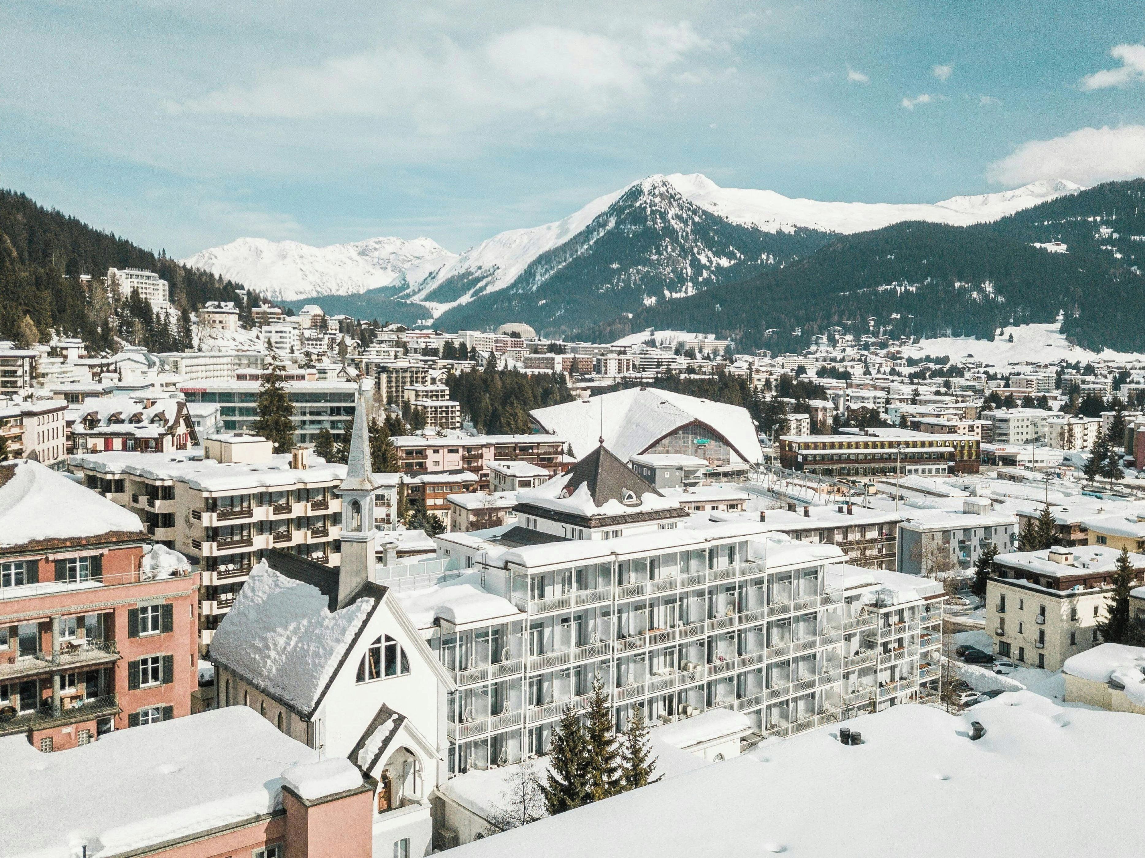 Un pueblo cubierto de nieve con edificios y montañas al fondo.