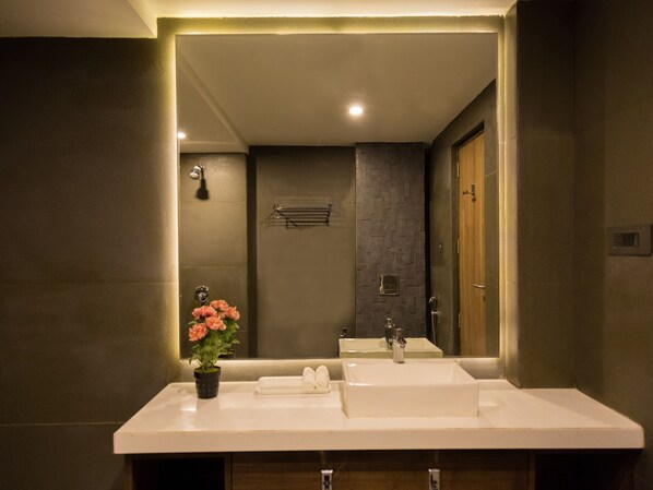 Un baño moderno con un espejo grande, dos lavamanos, una ducha y una planta en maceta.