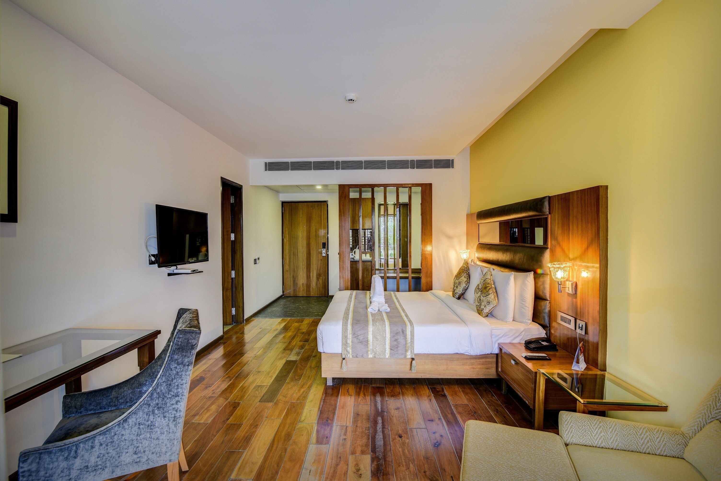 A hotel room with a bed, bedside table, TV, and seating area.