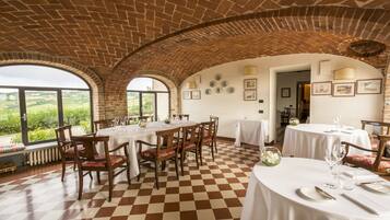 A dining area with brick arches, checkered flooring, and tables set for a meal.