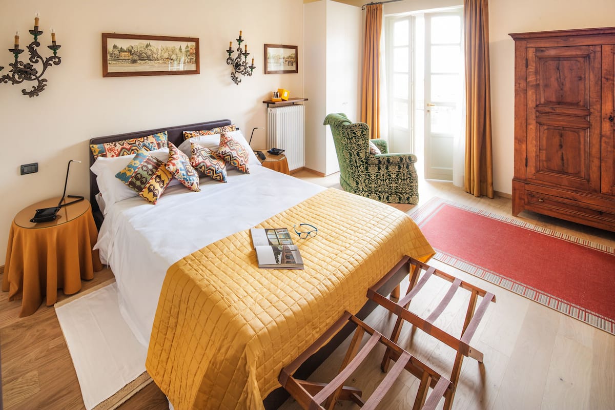 A bedroom with a large bed, a wooden chair, a wardrobe, and a radiator.