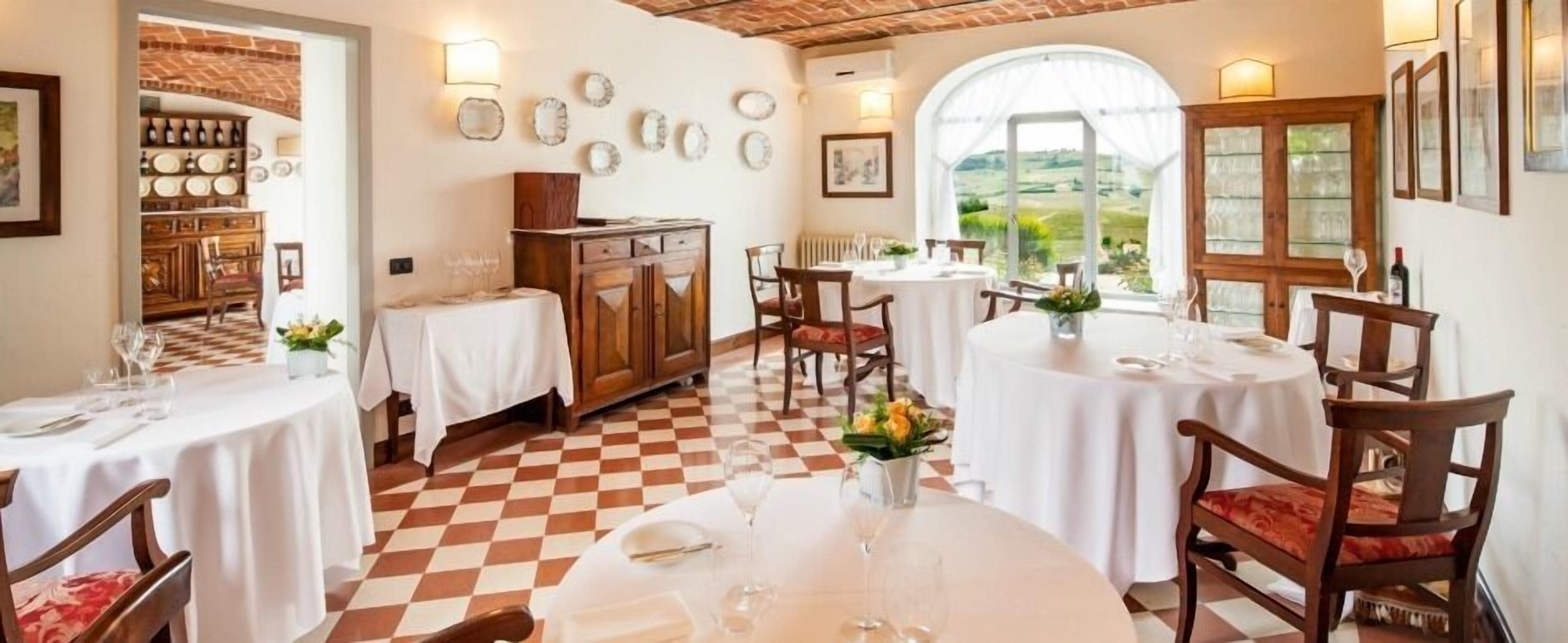 A dining area with checkered flooring, round tables, and wooden chairs.