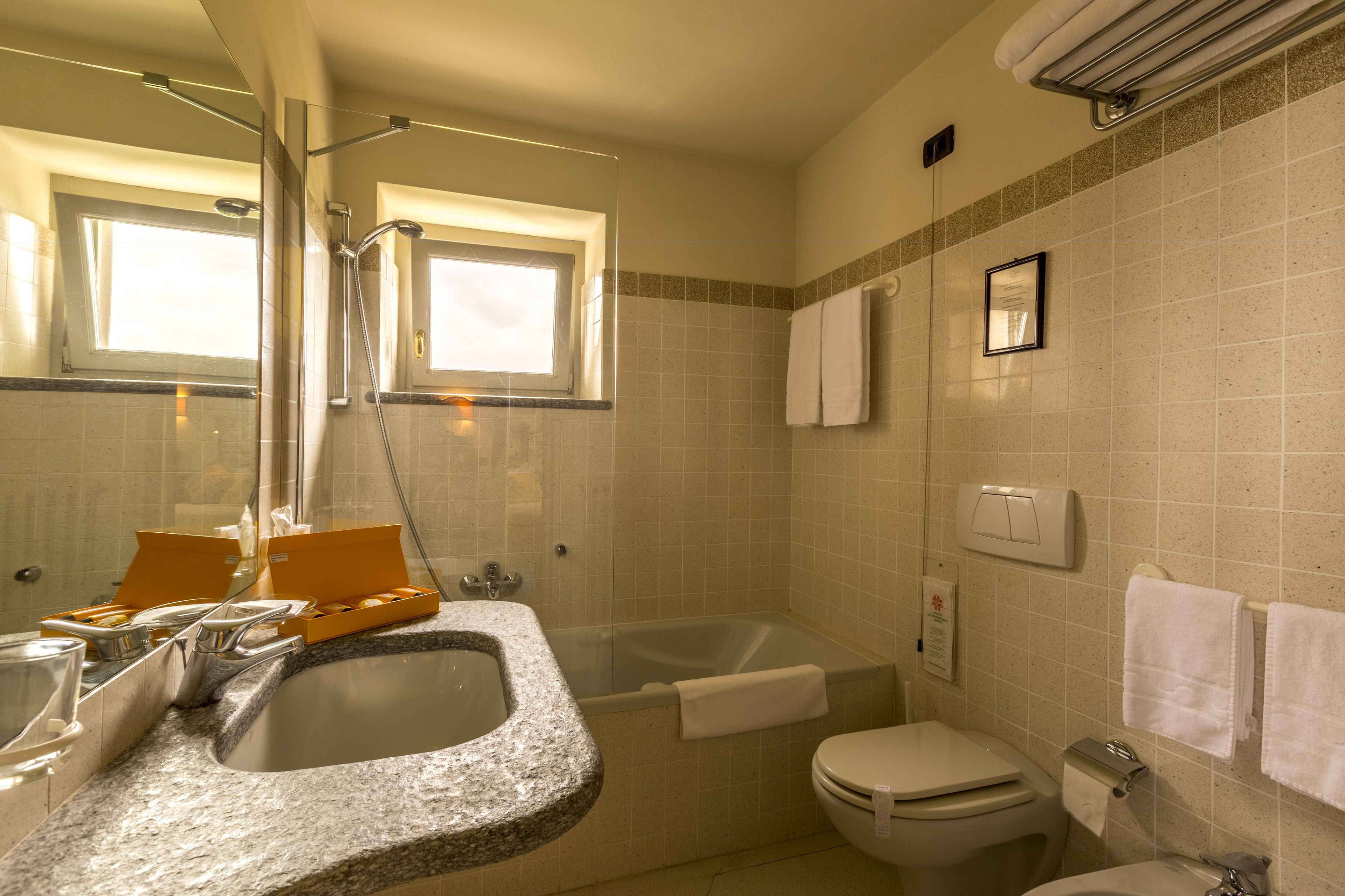 Een badkamer met een wastafel met granieten blad, een bad, een toilet en een douche.