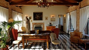 Una stanza con pavimento a scacchi, camino, lampadario e diversi tavoli e sedie.
