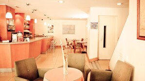 Rebost d'hotel amb zona de bar, seients i obres d'art a les parets.