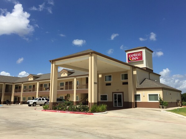 A hotel with a covered entrance, multiple balconies, and a parking lot.
