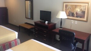 A hotel room with a bed, a desk with a computer, a chair, a lamp, a dresser, a mirror, and a painting on the wall. - Express Inn (Wharton)