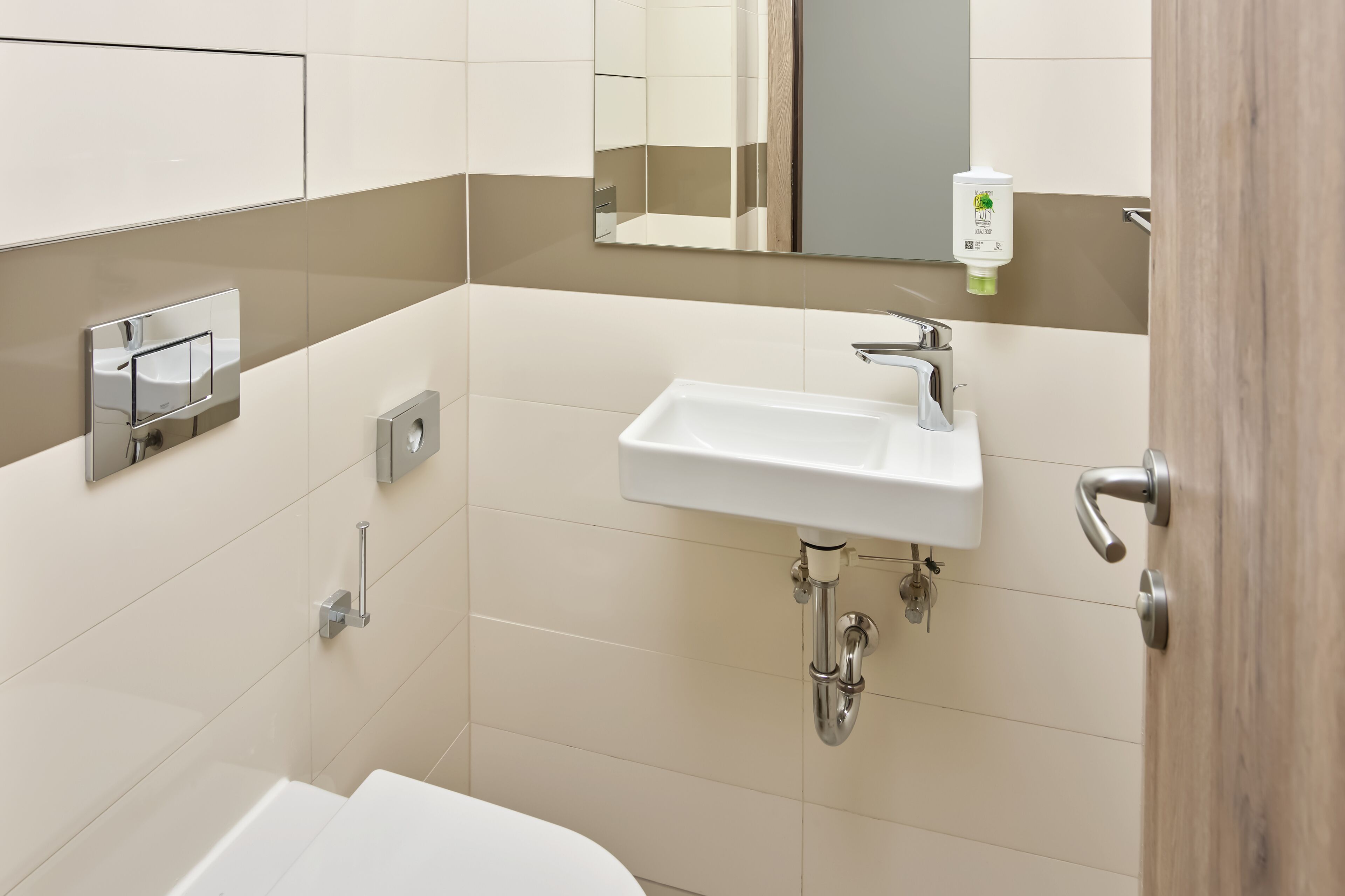 A modern bathroom with a white sink, mirror, and a hand dryer.