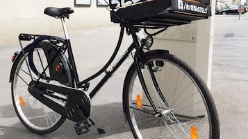 Een fiets met een bezorgdoos waarop 'SLEEP ENJOY' staat, geparkeerd voor een gebouw met een bord waarop 'HOTEL & BAR' staat.