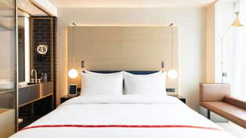 Een hotelkamer met een bed, nachtkastjes, een spiegel, een bankje en een raam.