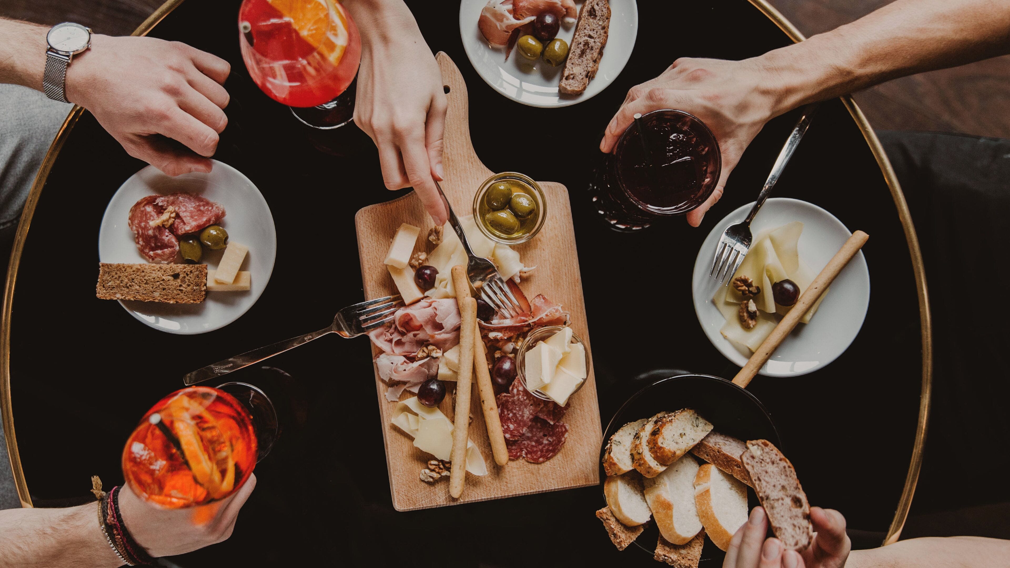 A group of people around a table with various food items and drinks.