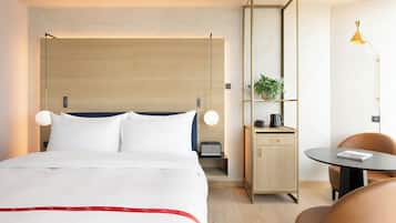 Habitación de hotel con cama, mesita de noche, lámpara y un escritorio pequeño con una silla.