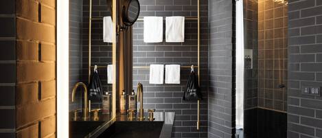 A modern bathroom with a large mirror, two sinks, a towel rack, and a shower area.