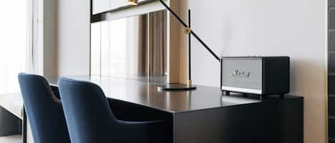 Una habitación moderna con escritorio, lámpara y altavoz.