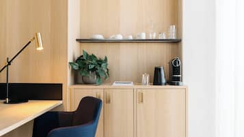 A modern kitchen with a wooden cabinet, a coffee machine, a plant, and a desk lamp.