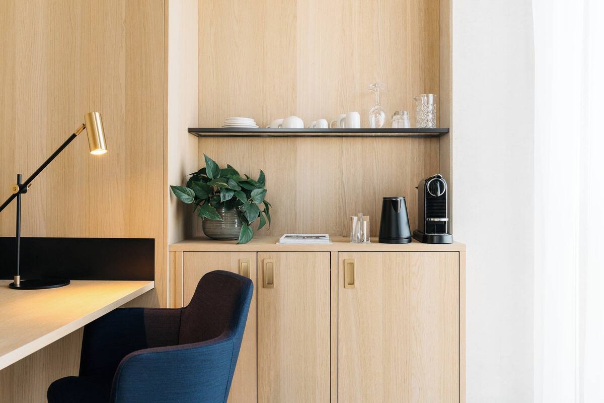 Une cuisine moderne avec un meuble en bois, une machine à café, une plante et une lampe de bureau.