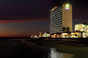 Un hotel de varios pisos con un letrero llamativo que dice 'Holiday Inn Resort' en la parte superior.