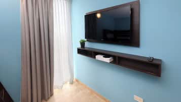 Une pièce avec un téléviseur fixé au mur, une étagère avec une plante et un interrupteur sur le mur.