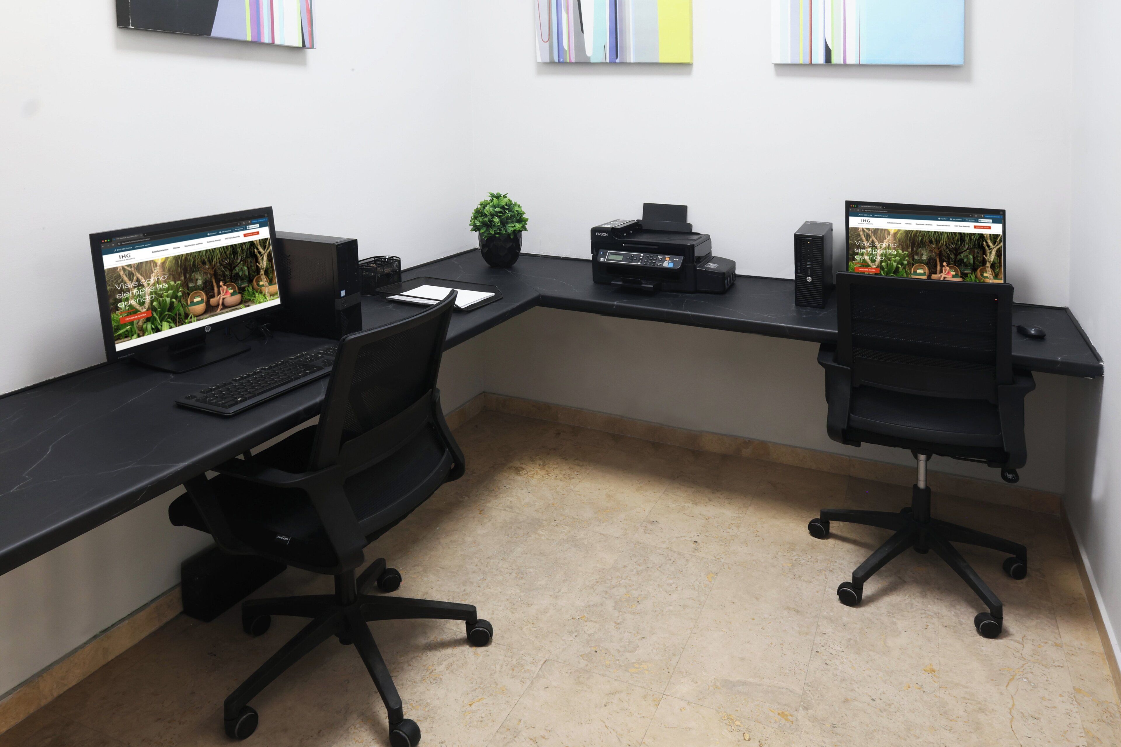 Un espace de travail comprenant deux bureaux, chacun équipé d’un écran d’ordinateur, d’un clavier et d’une souris. Une plante en pot est posée sur l’un des bureaux.