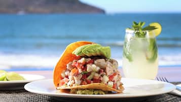 Un taco à l’avocat et une boisson sur une table au bord de l’océan.