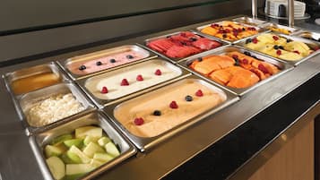 A buffet with various food options including fruits, yogurt, and other dishes.