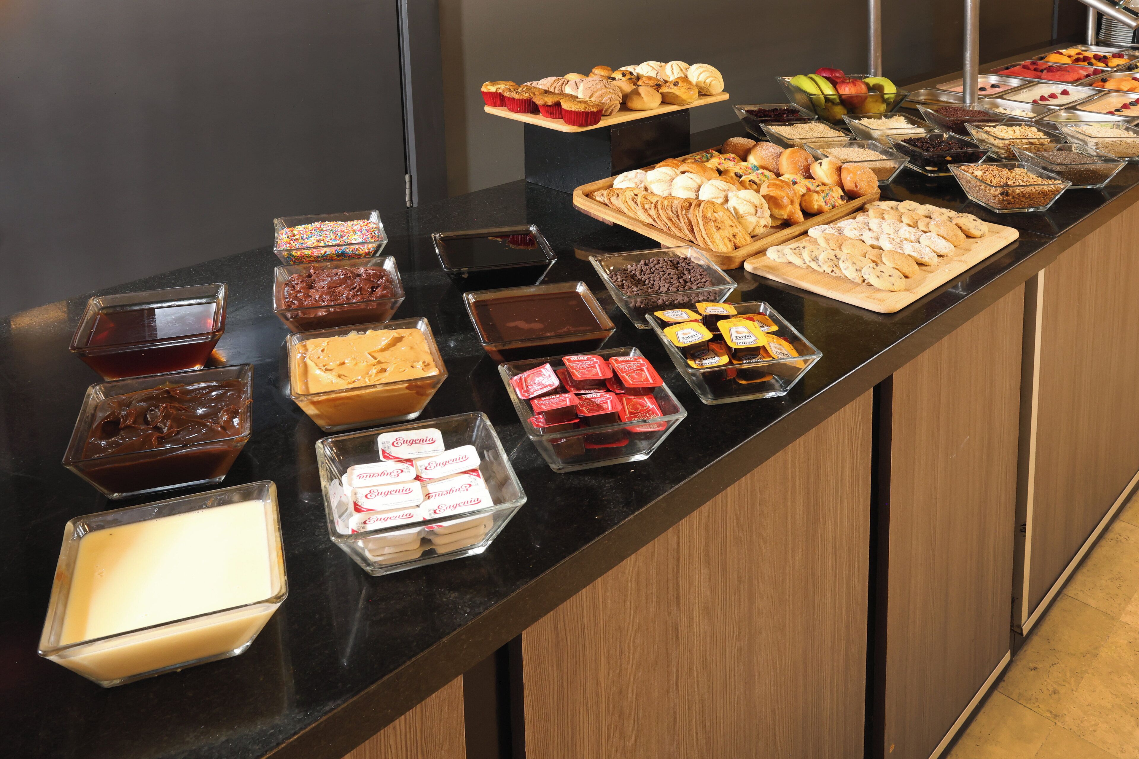 A buffet with various food items including pastries, fruits, and desserts.