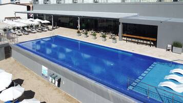 Una piscina al aire libre, sillones reclinables de piscina