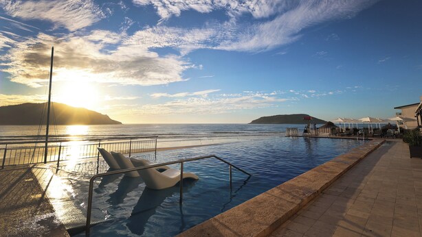 Una piscina amb vista al mar i a les muntanyes durant el capvespre.