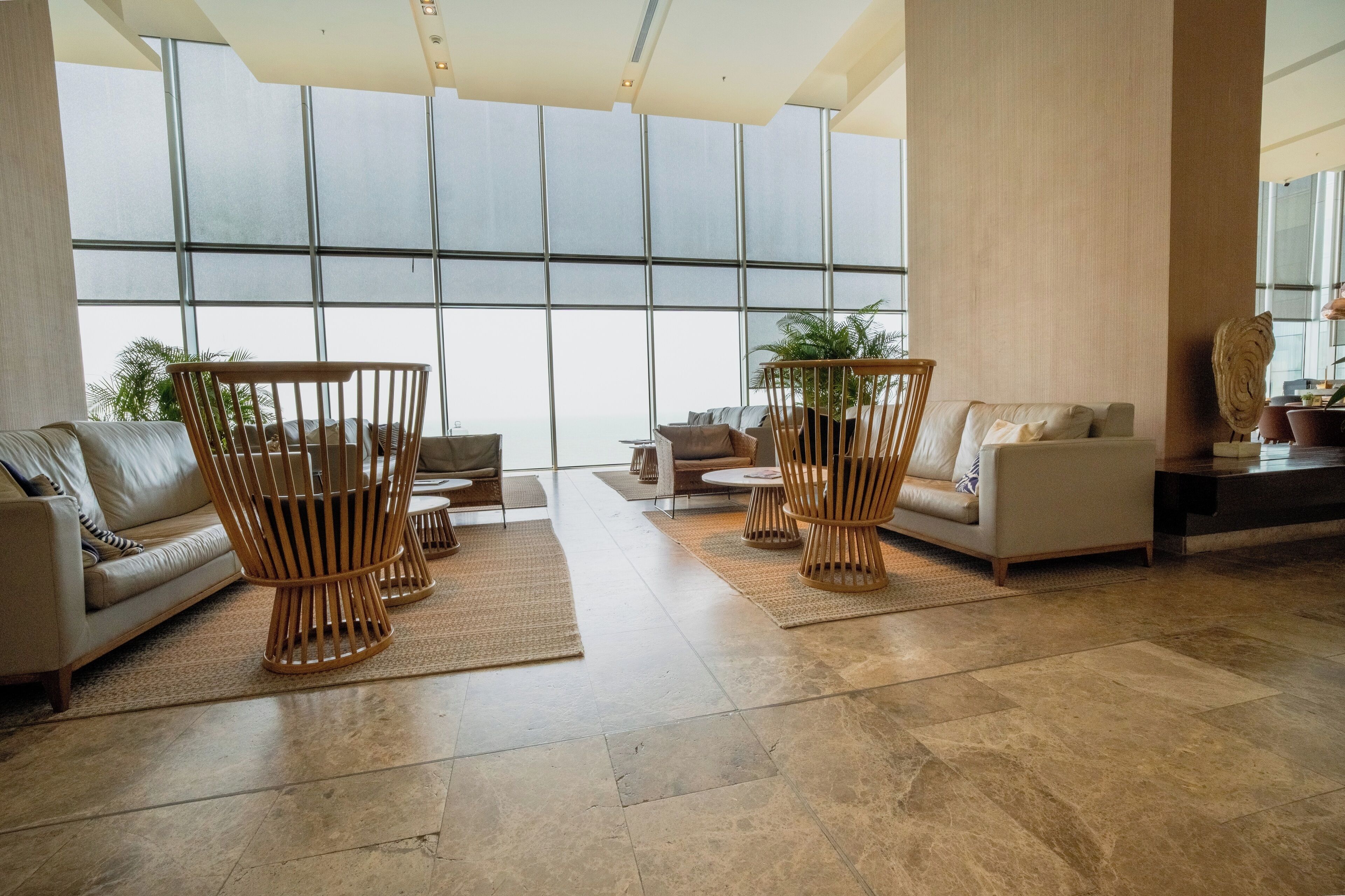 A spacious lobby with large windows, a high ceiling, and a modern interior design.
