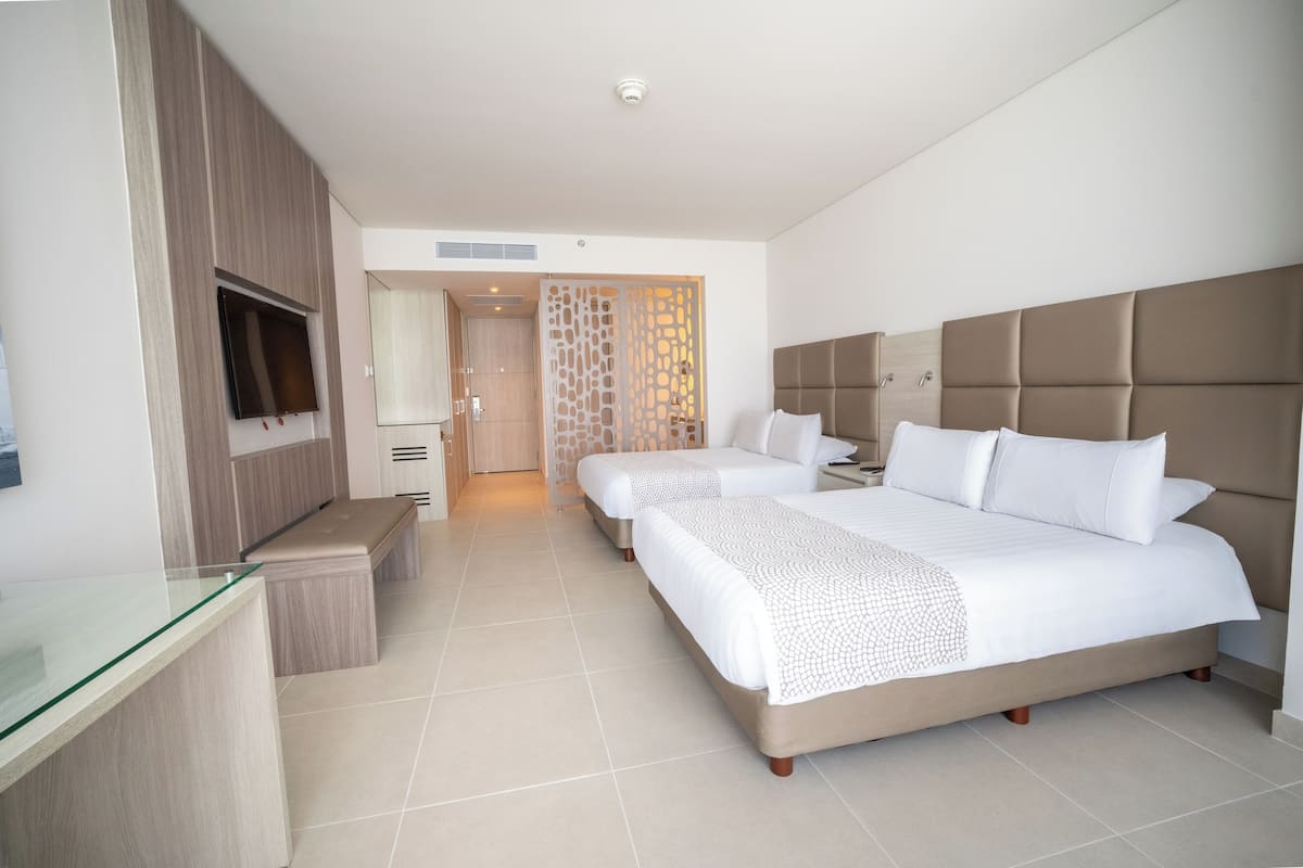 A hotel room with a large bed, a TV, a desk, and a bathroom visible through a door.