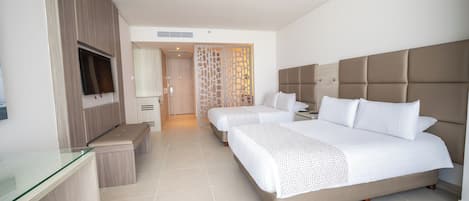 A hotel room with a large bed, a TV, a desk, and a bathroom visible through a door.