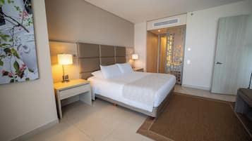 A hotel room with a bed, nightstands, a lamp, a door, and a wall decoration.