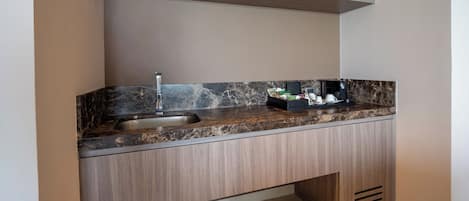 Una cocina moderna con encimera de mármol, un fregadero y una cafetera.
