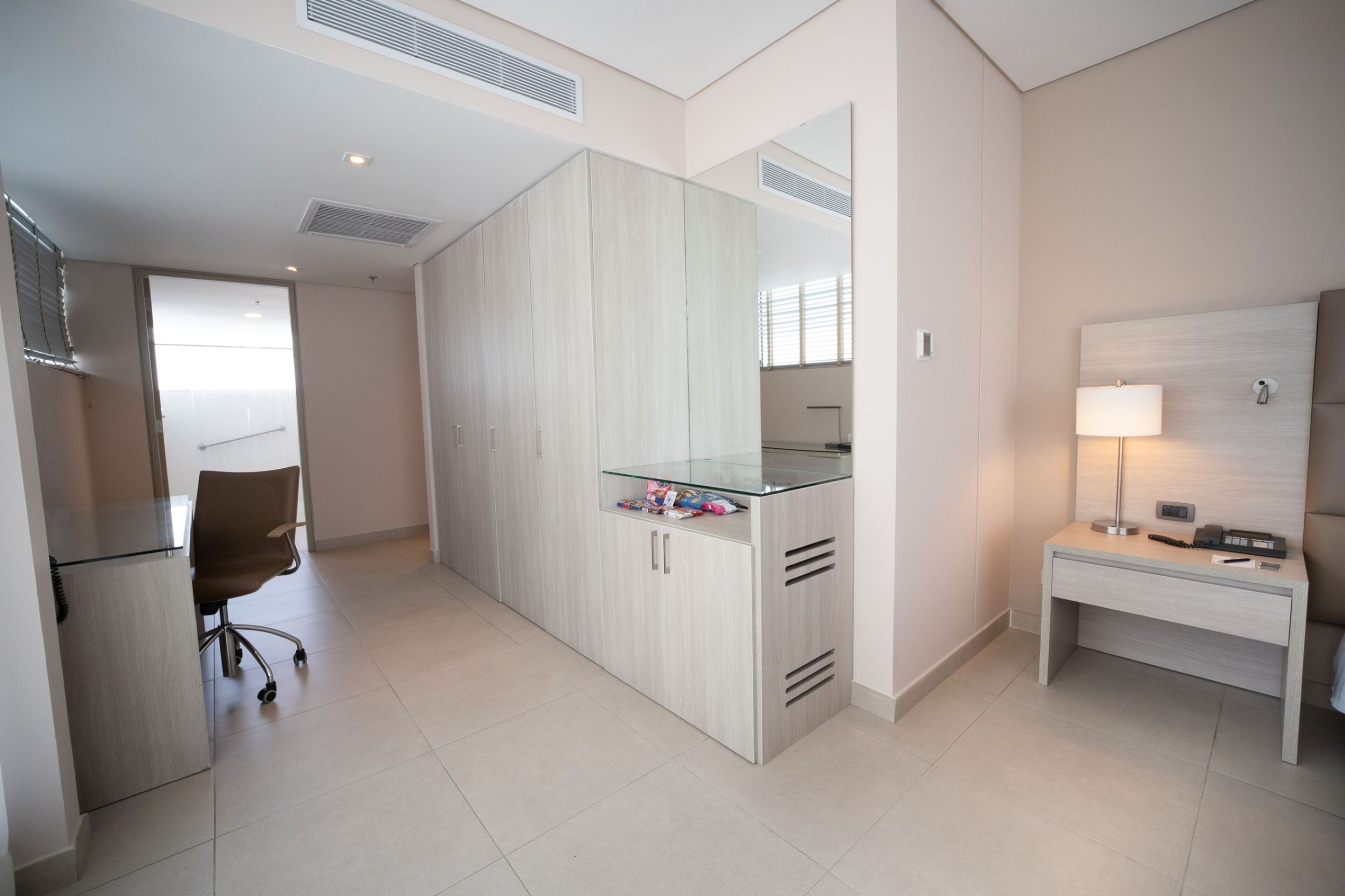 Une chambre d’hôtel moderne équipée d’une grande armoire, d’un bureau avec une lampe et d’une chaise.