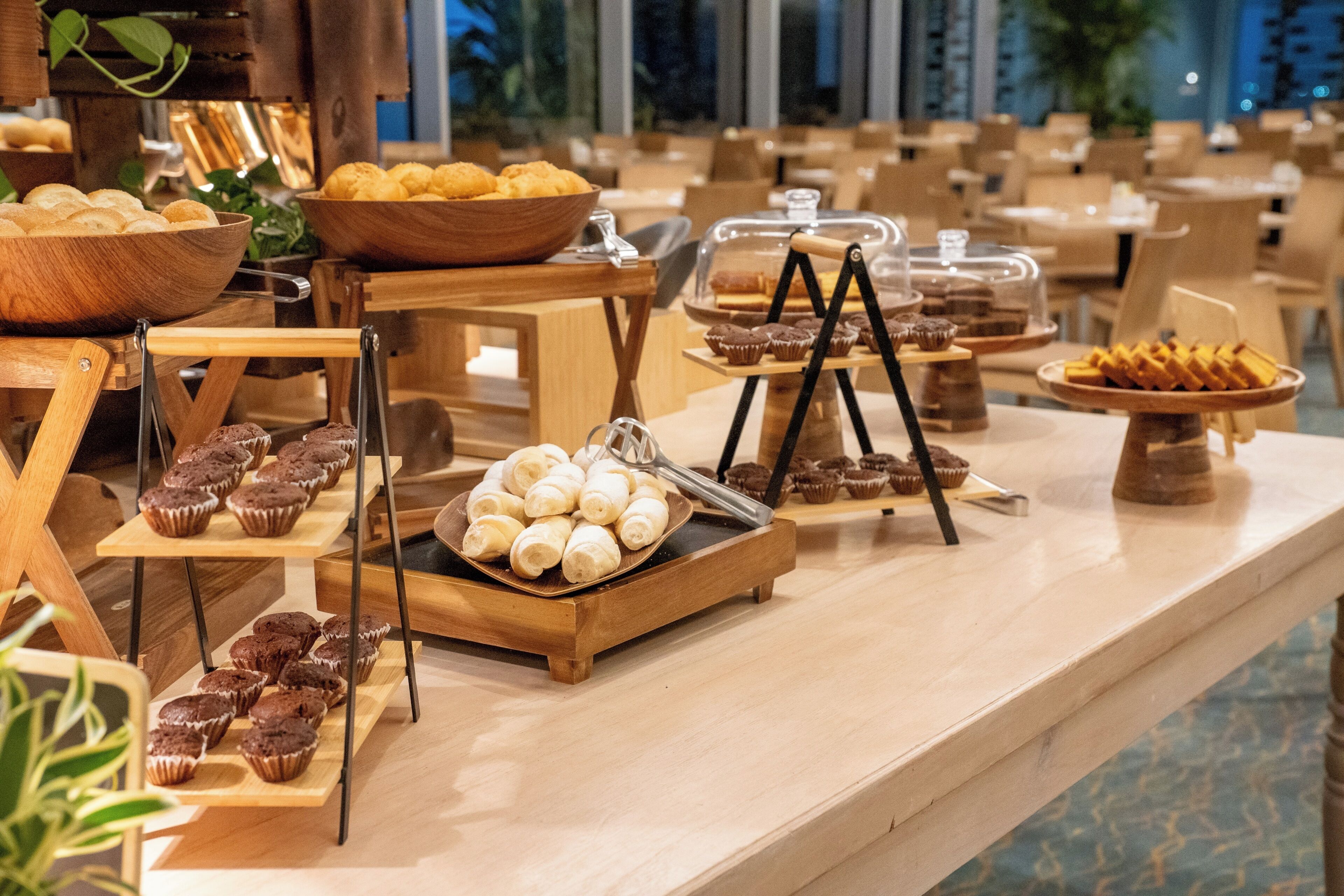 A buffet setup with various baked goods displayed on wooden stands and trays.