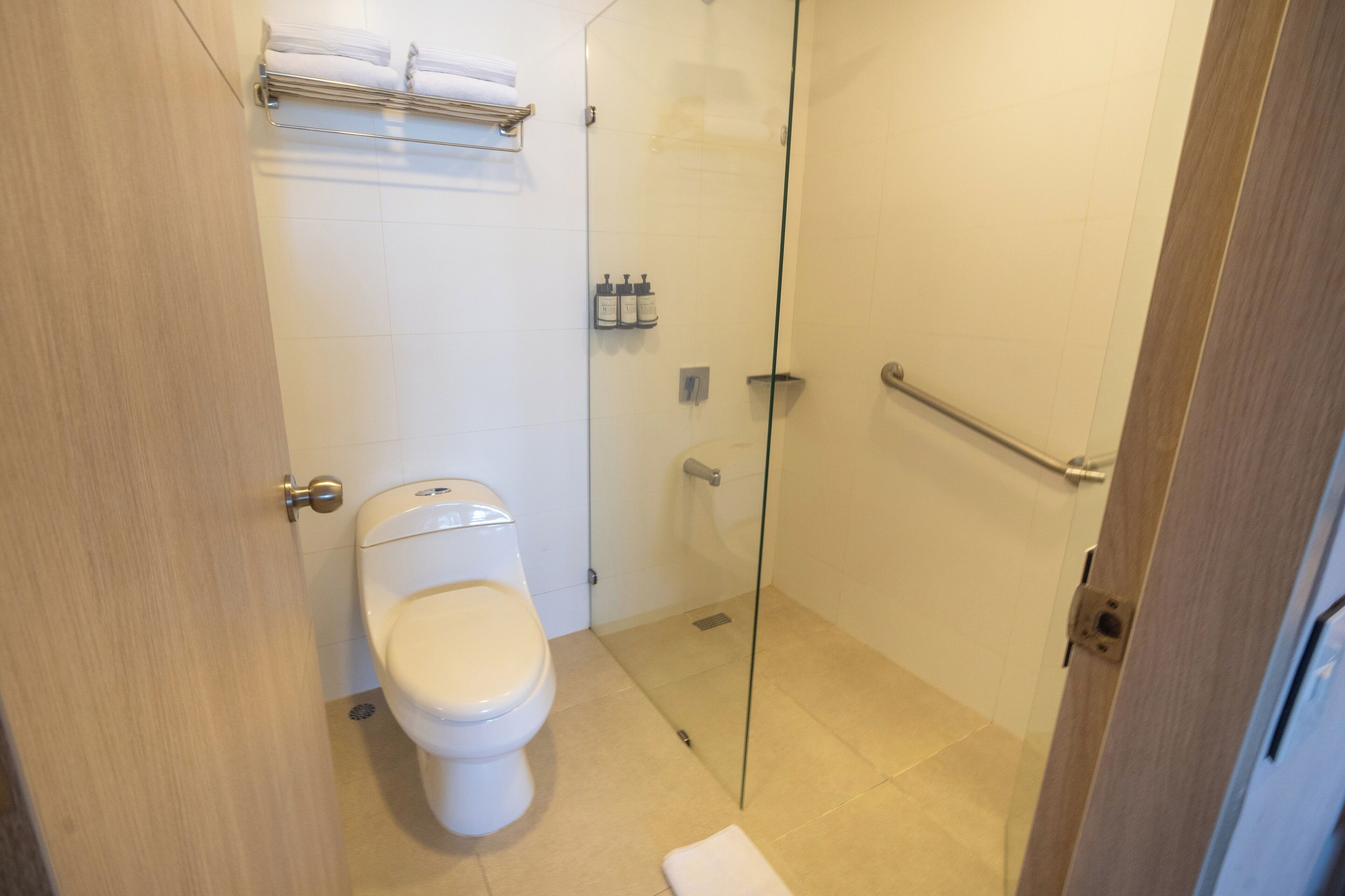 A bathroom with a toilet, a glass shower enclosure, and a towel rack.