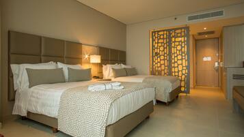 A hotel room with two beds, a large headboard, a decorative partition, and a bench.