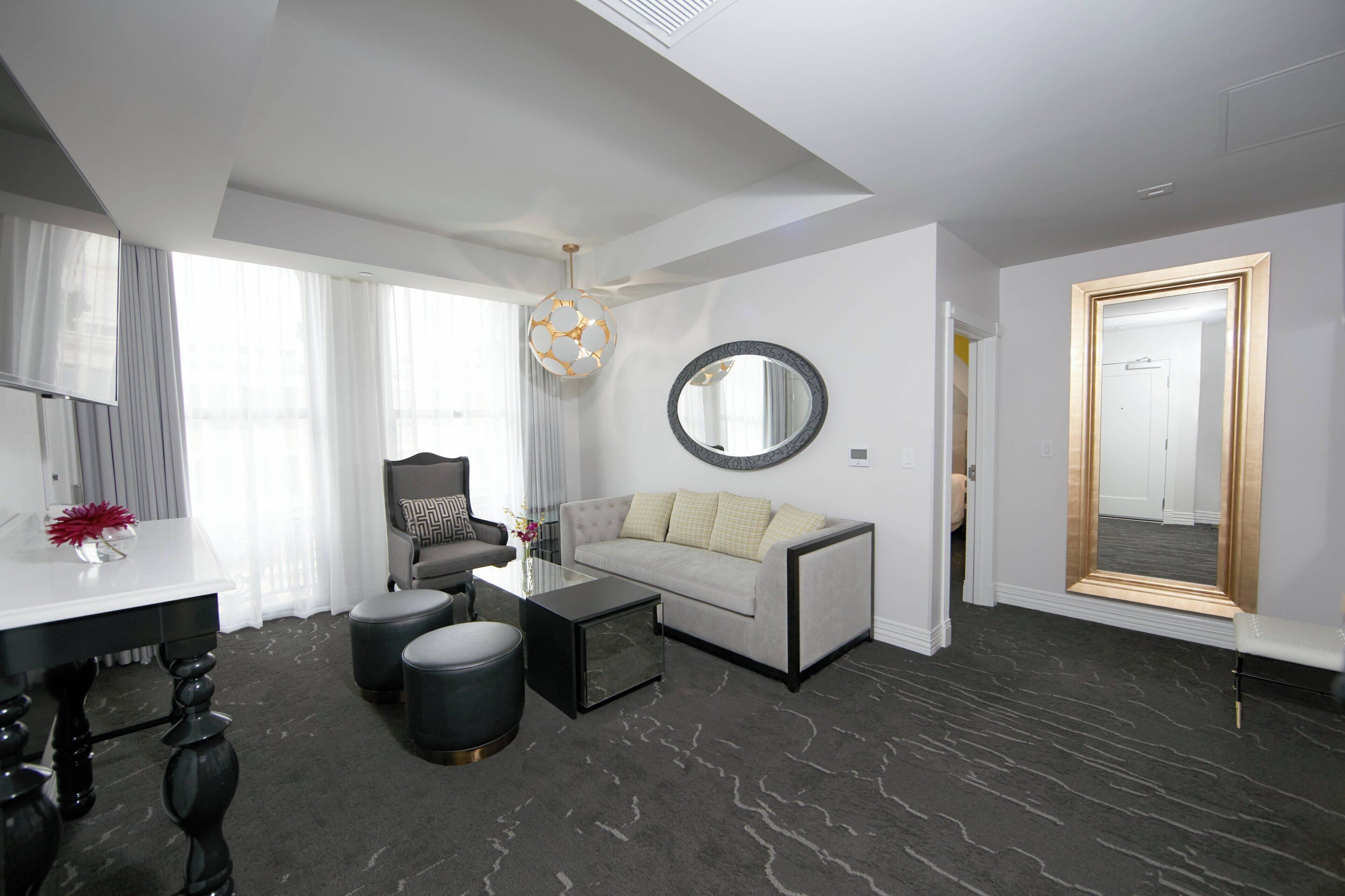 A modern living room with a sofa, coffee table, ottoman, and a dining area with a table and chairs.