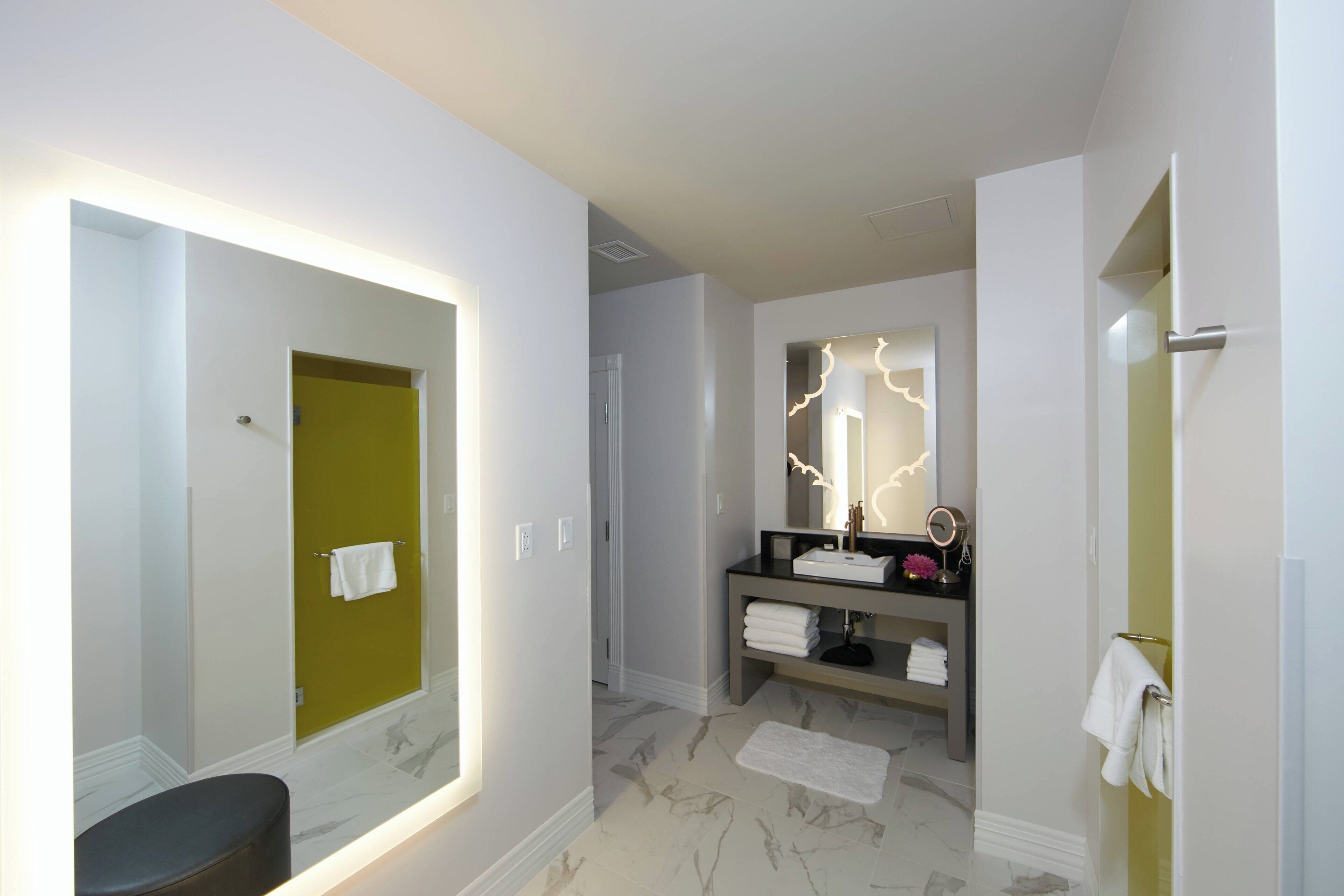 Une salle de bain moderne avec un grand miroir, un meuble-lavabo et un porte-serviettes.