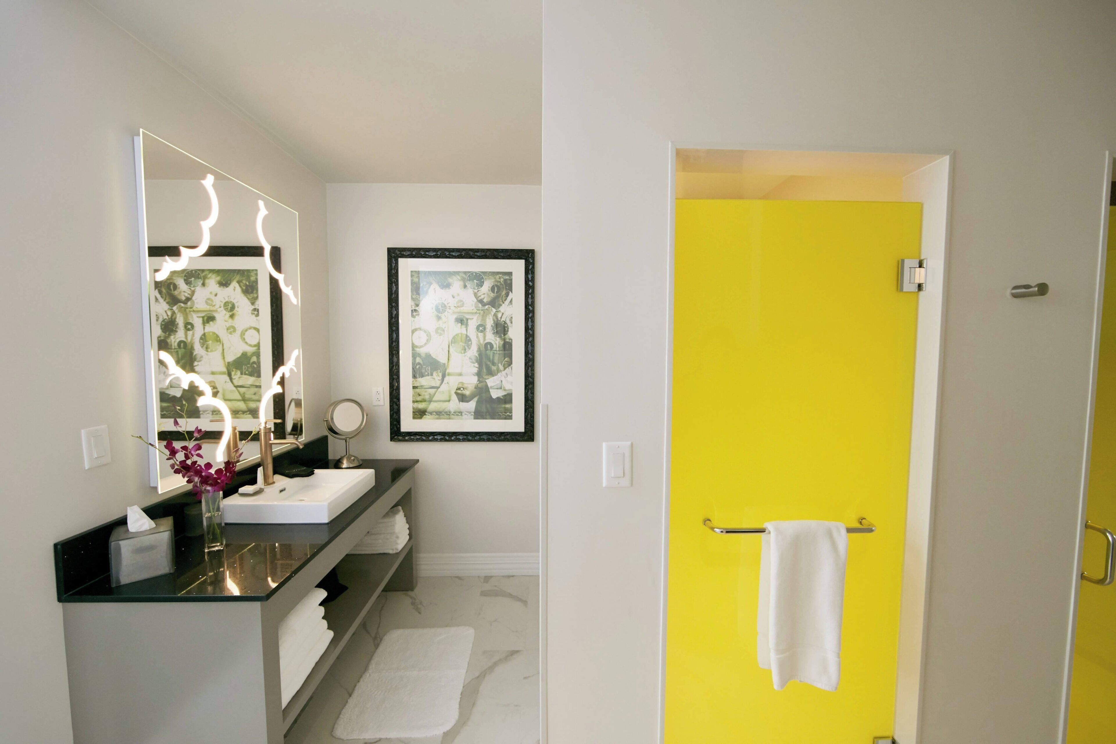 Une salle de bain avec un miroir, un lavabo et une porte jaune.