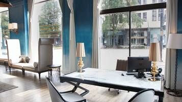 Una habitación de hotel moderna con un ventanal grande, un escritorio de mármol, dos sillas, una computadora y una lámpara.
