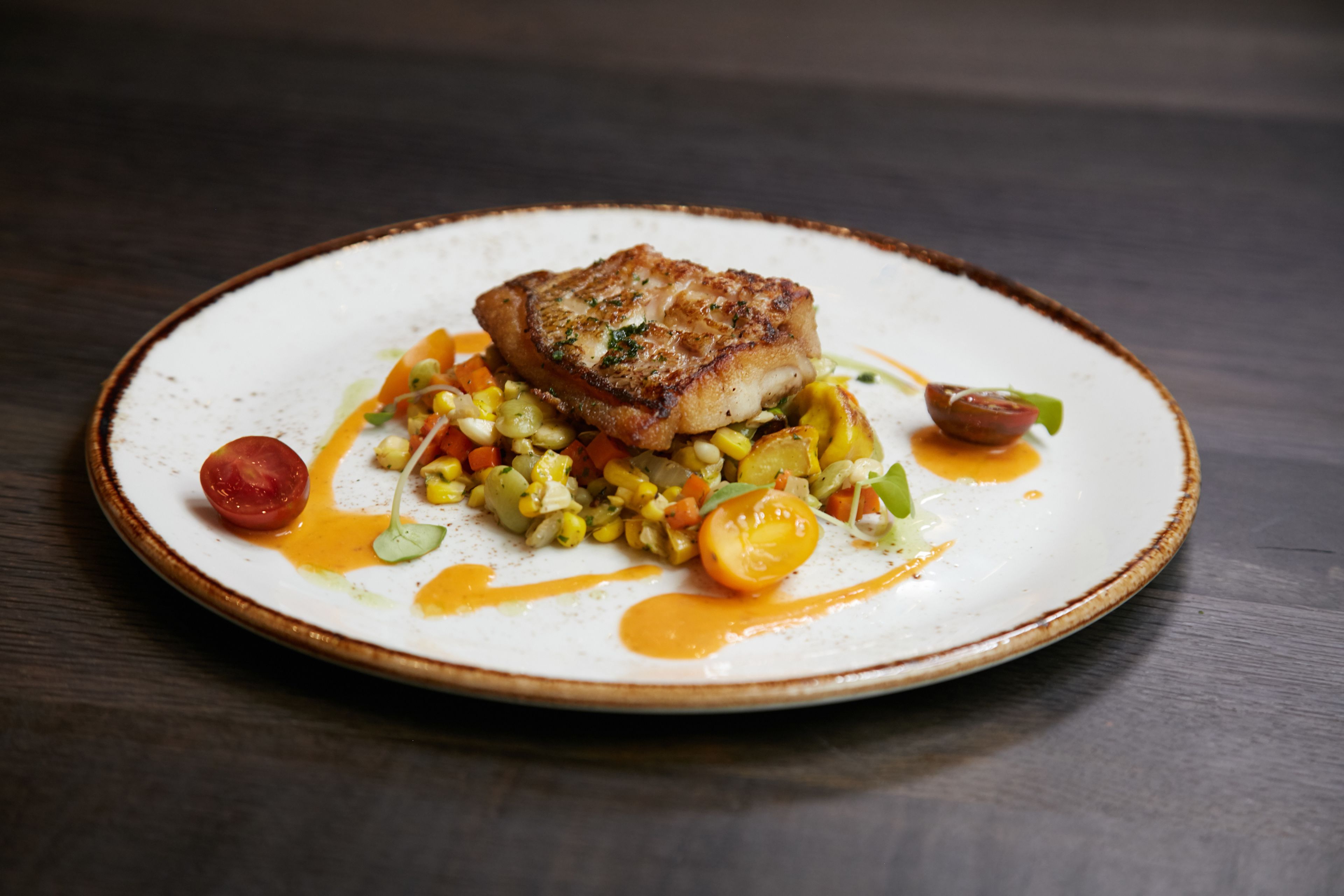 A plate of food with a piece of meat, vegetables, and sauce.
