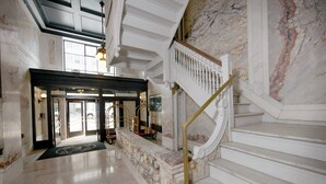 A grand lobby with marble floors, a grand staircase, and a reception area. - Elyton Hotel, Autograph Collection by Marriott (Birmingham)