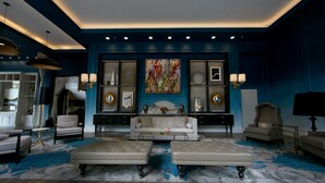 A modern living room with a sofa, two ottomans, a coffee table, and a large abstract painting on the wall. - Elyton Hotel, Autograph Collection by Marriott (Birmingham)